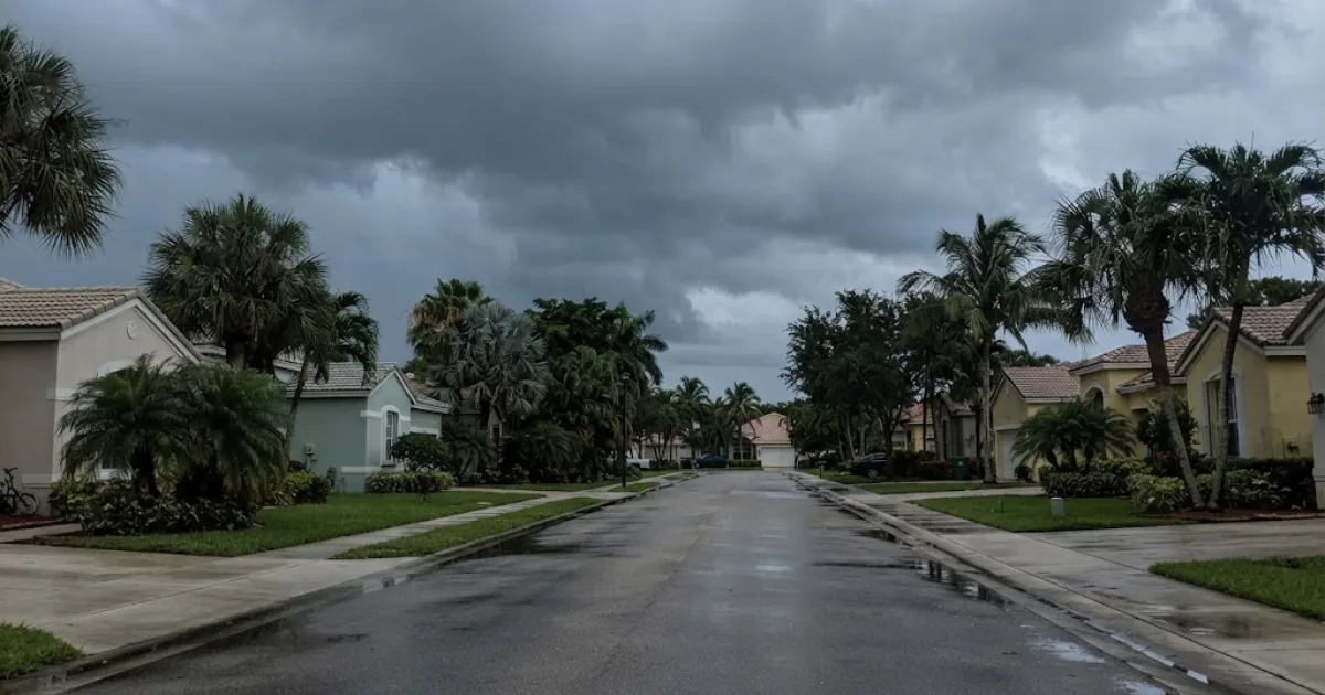 Storm clouds gathering over a Florida neighborhood street lined with palm trees