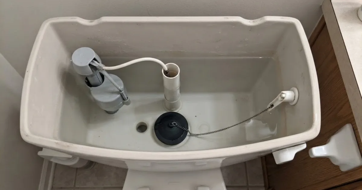 Open toilet tank showing the fill valve and overflow tube