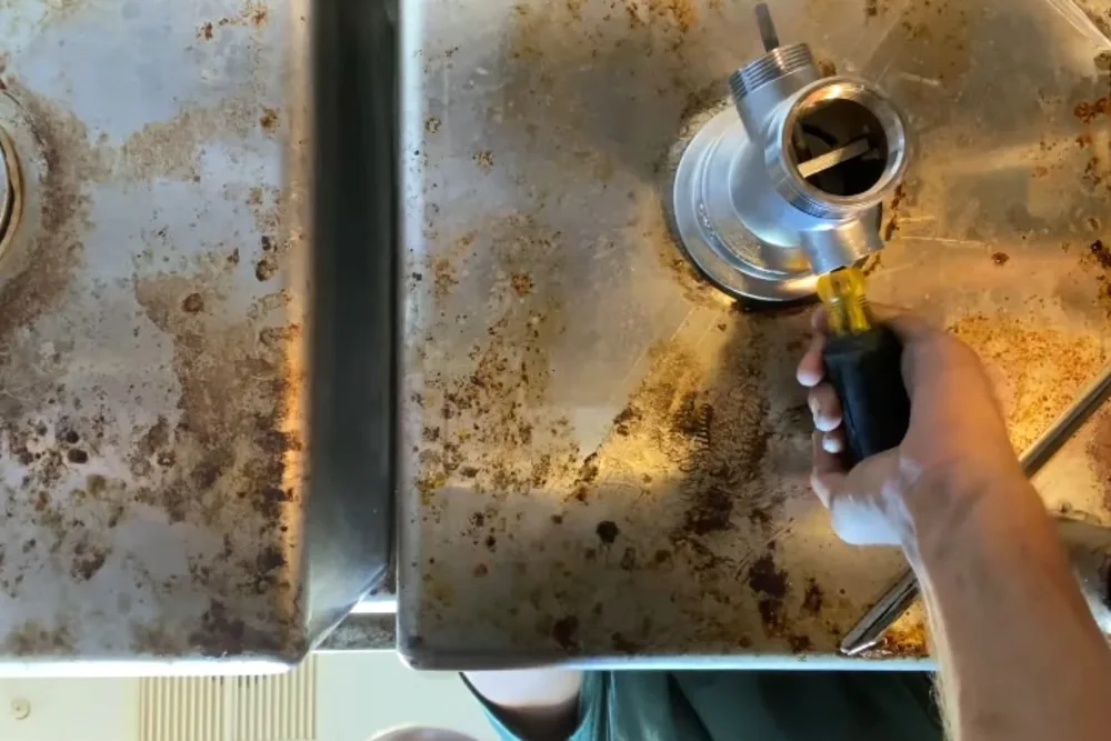Plumber soldering a copper fitting on a commercial kitchen sink installation