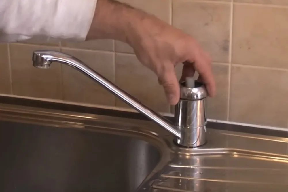 Close-up of a hand adjusting a kitchen faucet during a repair