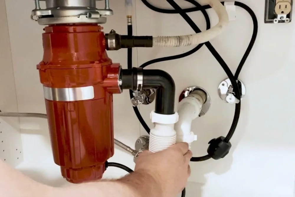 Garbage disposal unit installed beneath a kitchen sink with supply lines connected