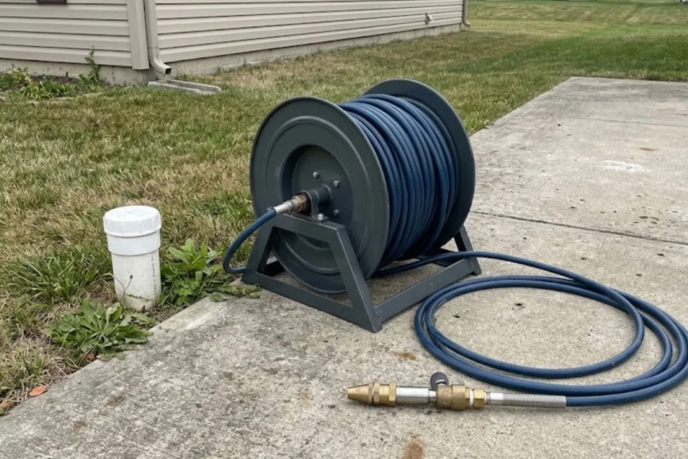 Hydro jetting hose reel and nozzle equipment staged outside a home cleanout