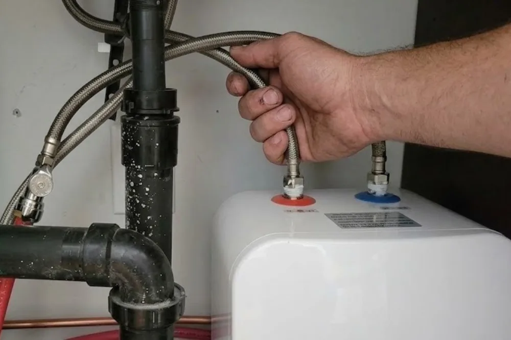 Plumber connecting flexible supply lines to a new residential water heater installation